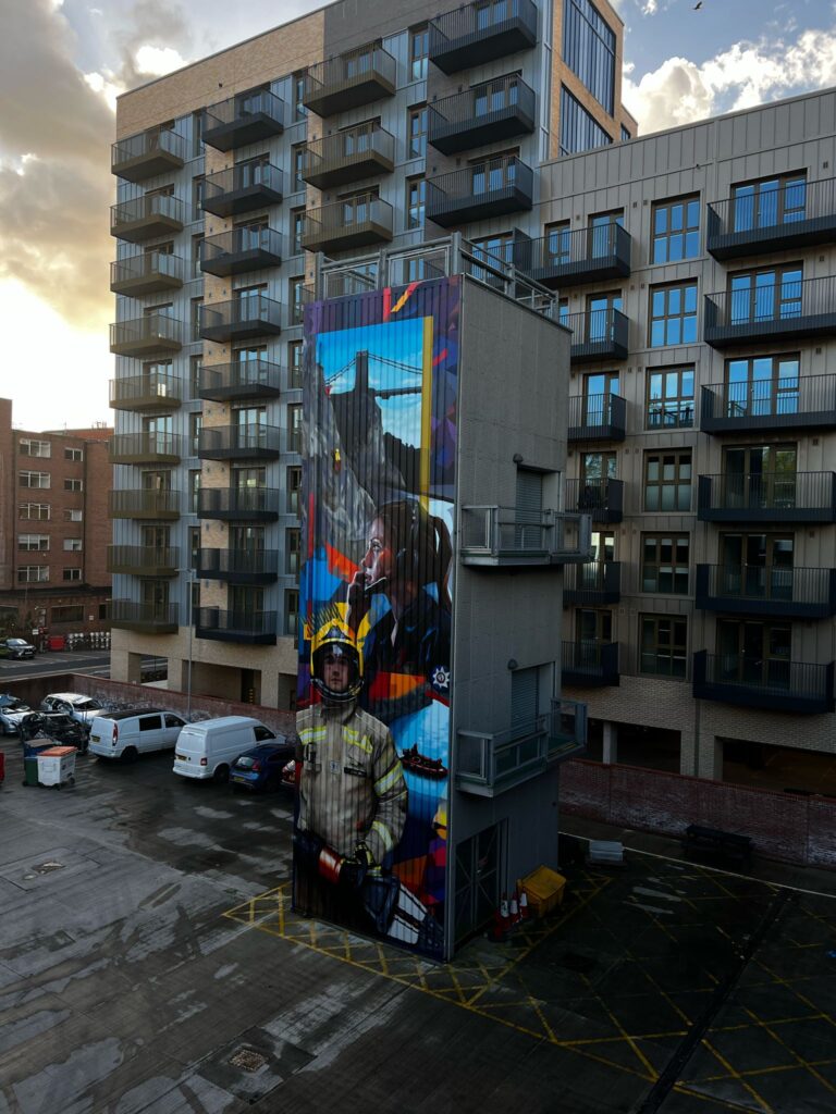 Graffiti style mural on Temple Fire Stations Training Tower, featuring a control fire operator and firefighter with depictions of real life incidents.