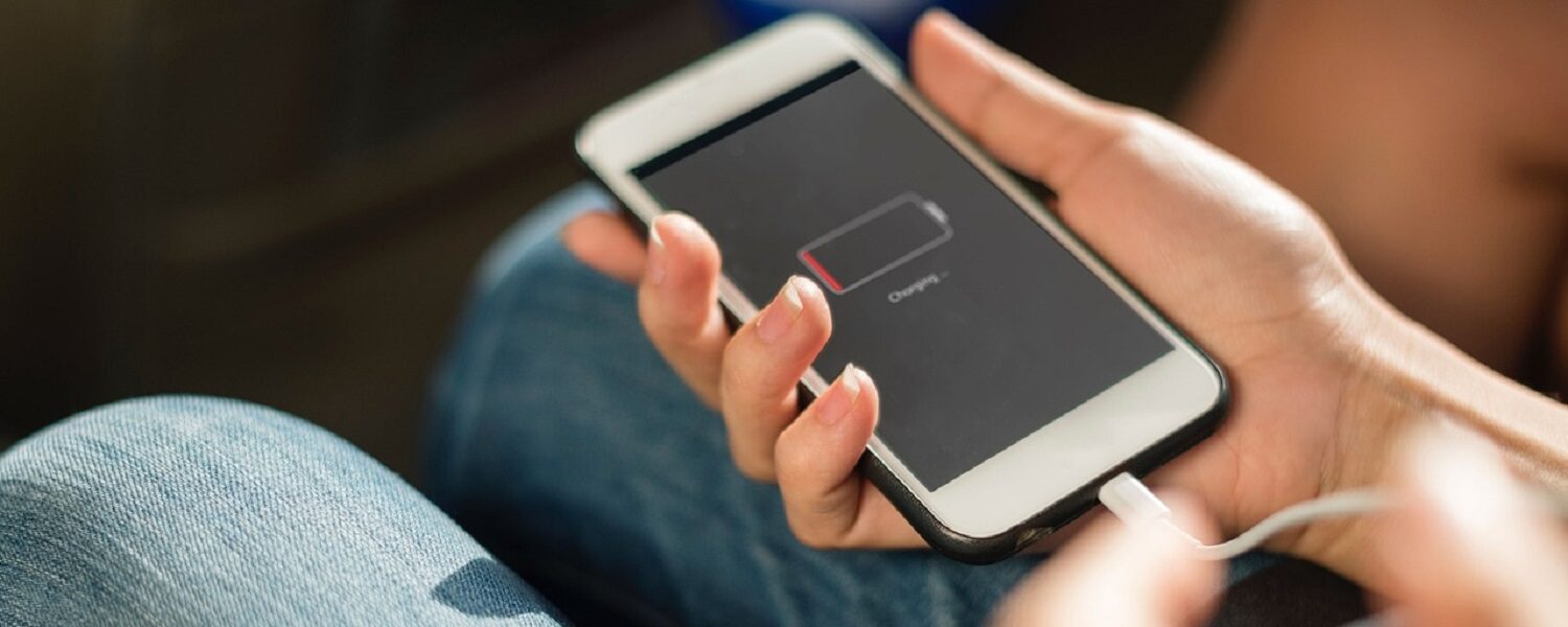 person holding smartphone with low battery plugging it in to chargee