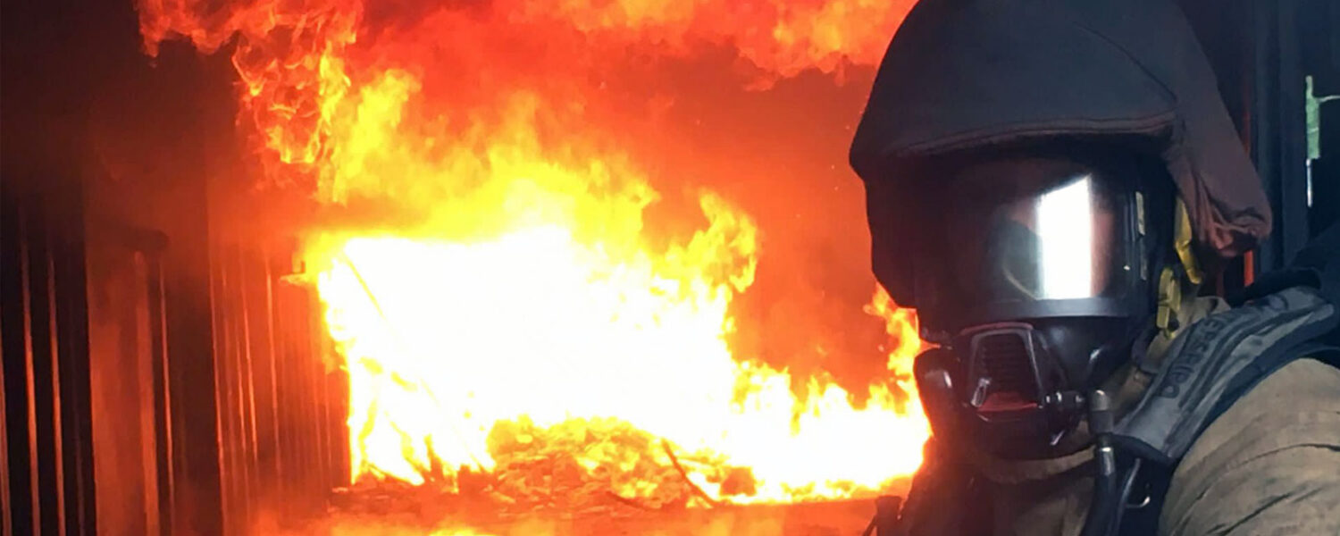 Firefighter if full kit with fire in background