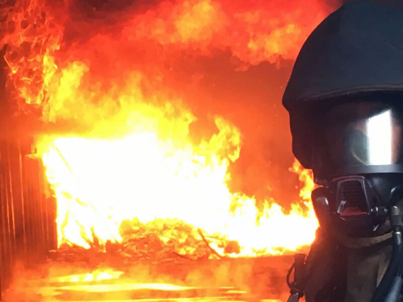 Firefighter if full kit with fire in background