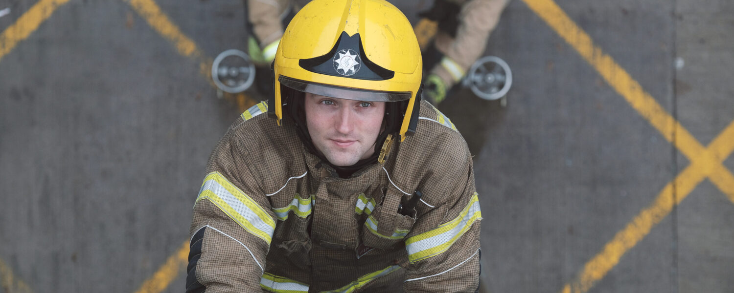 White male Firefighter climbing ladder in full kit