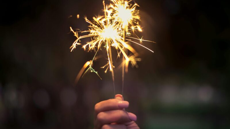 Hand holding two lit sparklers