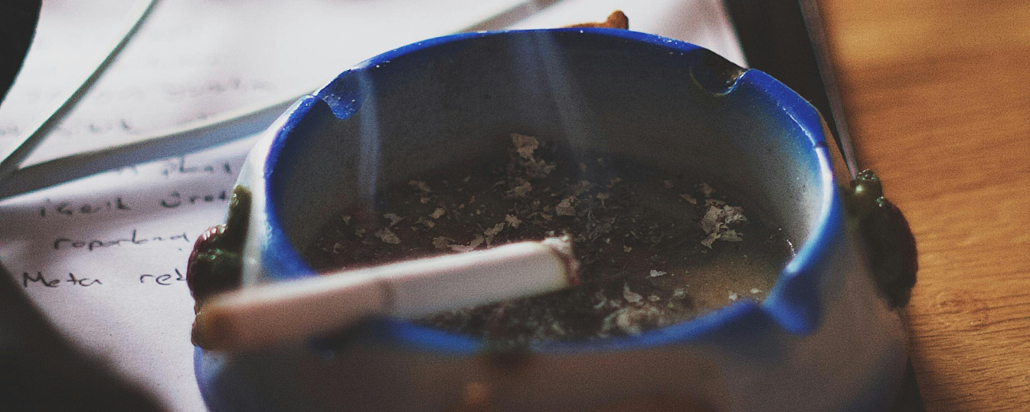 blue ashtray with lit cigarette