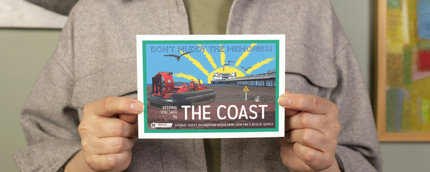 person holding postcard with vintage themed design that says 'don't muddy the memories' and ';keeping you safe by the coast' with an image of a fire service hovercraft on Weston-super-Mare beachfront
