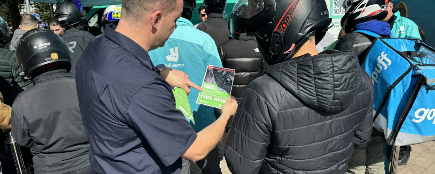 Firefighter giving charge safety advice to a Deliveroo rider