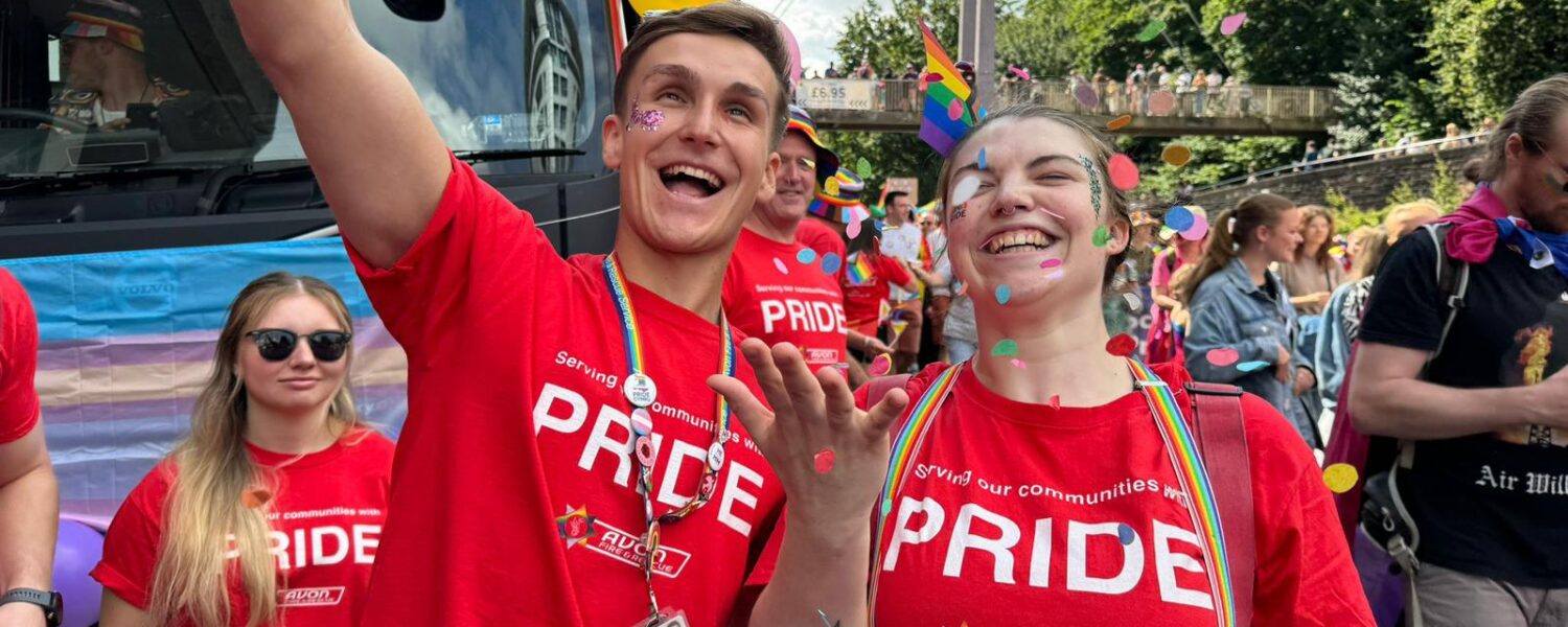 Two members of Avon Fire & Rescue Service staff attending the parade march during Bristol Pride 2024
