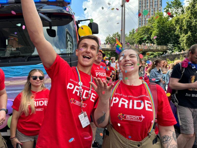 Two members of Avon Fire & Rescue Service staff attending the parade march during Bristol Pride 2024