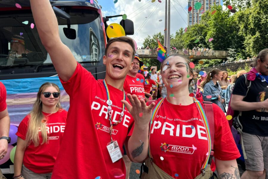 Two members of Avon Fire & Rescue Service staff attending the parade march during Bristol Pride 2024