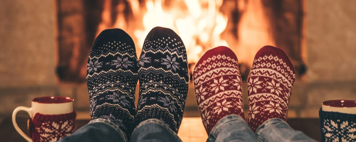 Image of feet in Christmas socks in front of the fire keeping warm.
