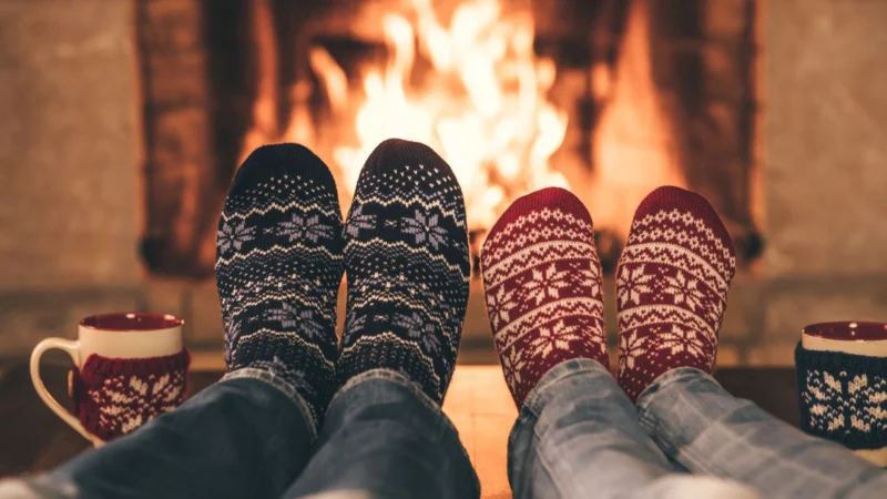 Image of feet in Christmas socks in front of the fire keeping warm.