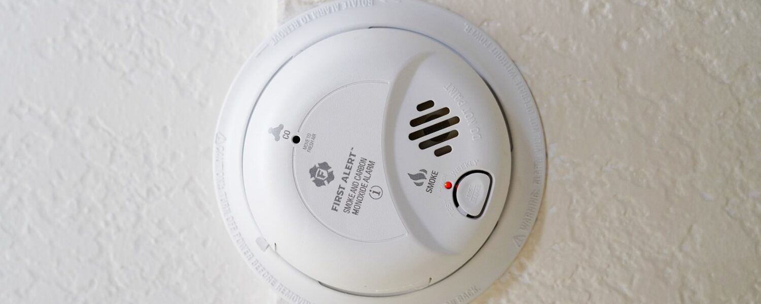 a dual smoke and carbon monoxide alarm on a textured ceiling
