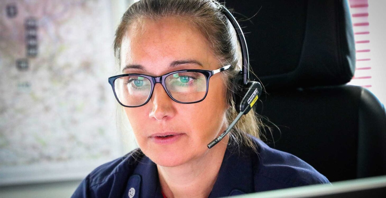 Woman in headset looking at computer screen taking emergency call