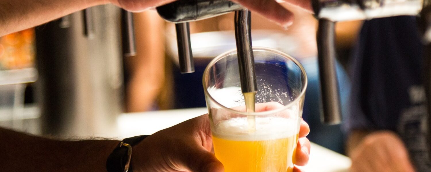 hands using tap to pour pint of beer