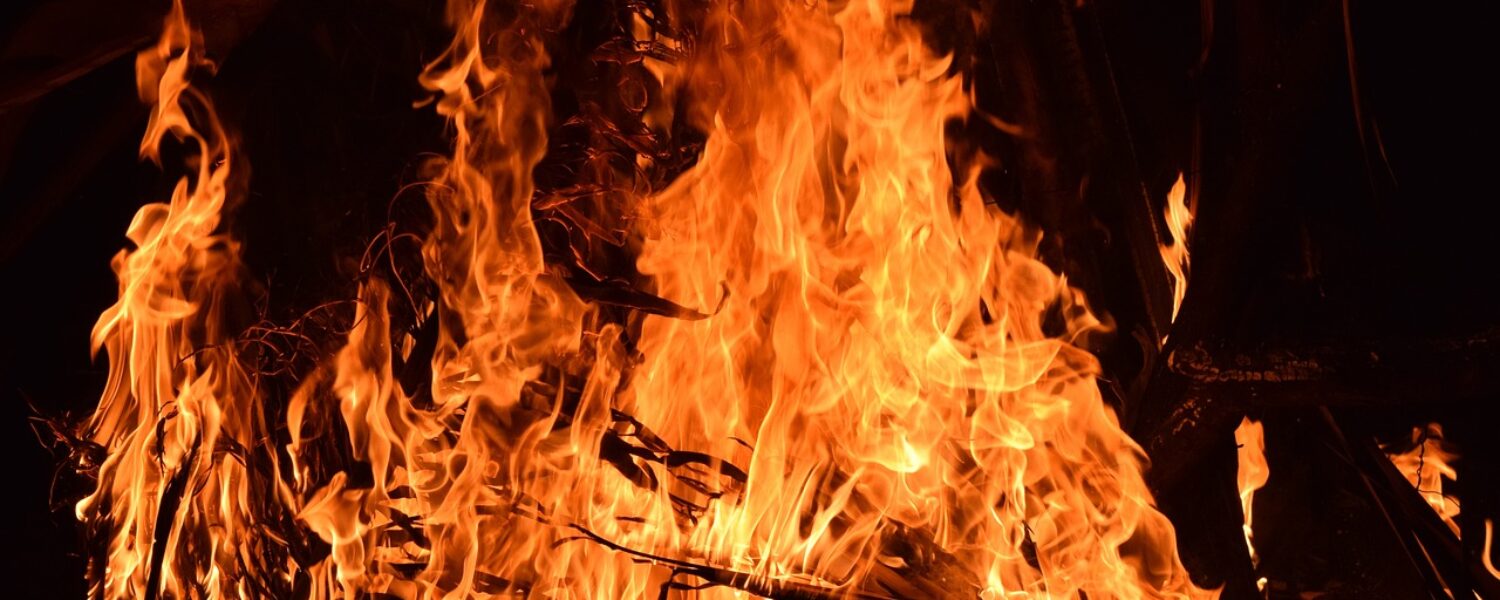 large bonfire with thick orange flames and sticks burning