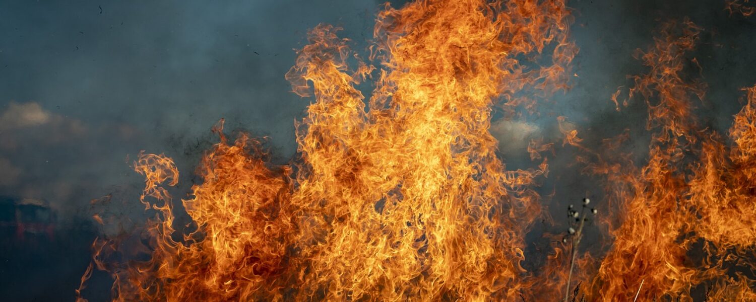 section of grass on fire with smoke in the background