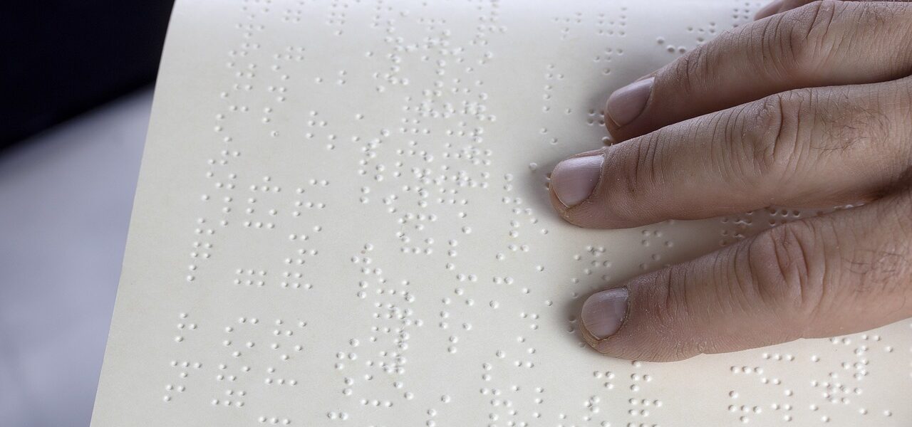 Person with fingers reading braille in book