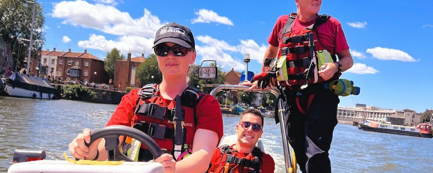 Female Firefighter driving recue boat with two other male firefighters