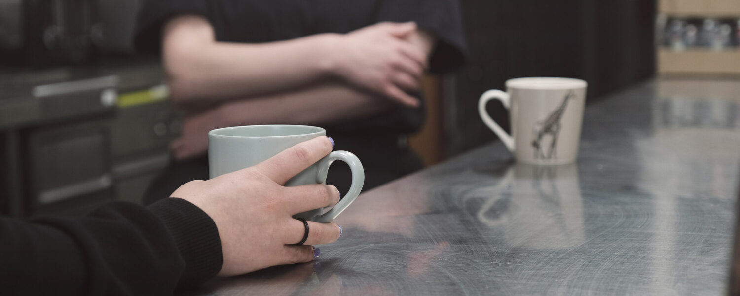 picture of two people having tea, close up of mugs of tea and peoples hands