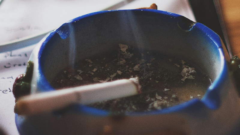 blue ashtray with lit cigarette