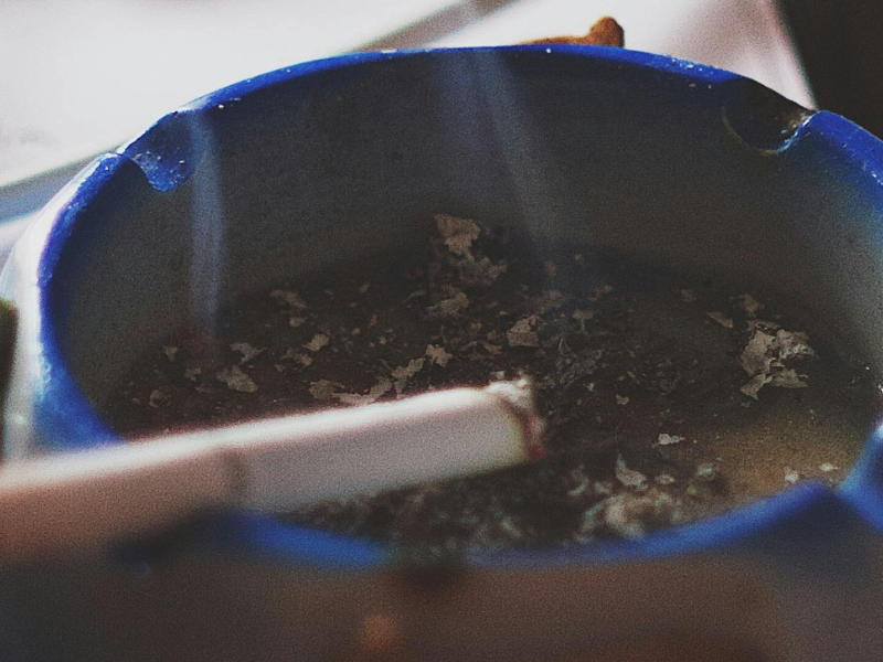 blue ashtray with lit cigarette