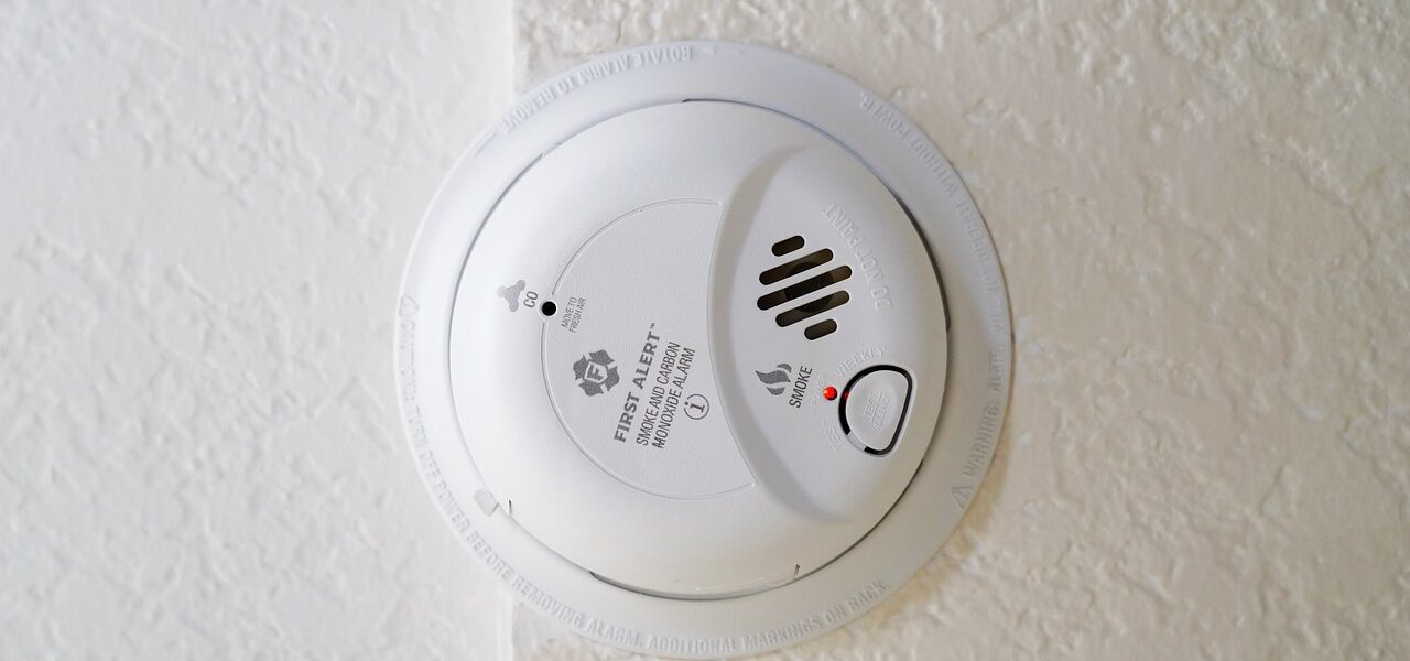 a dual smoke and carbon monoxide alarm on a textured ceiling