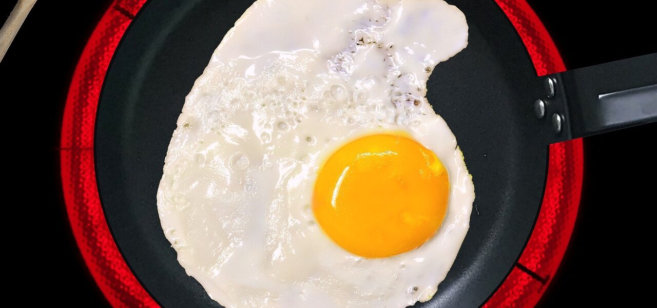 induction hob ring glowing red with frying pan on top of it containing a fried egg