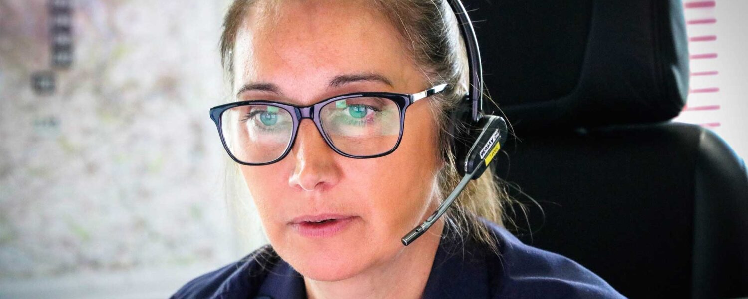 Woman in headset looking at computer screen taking emergency call